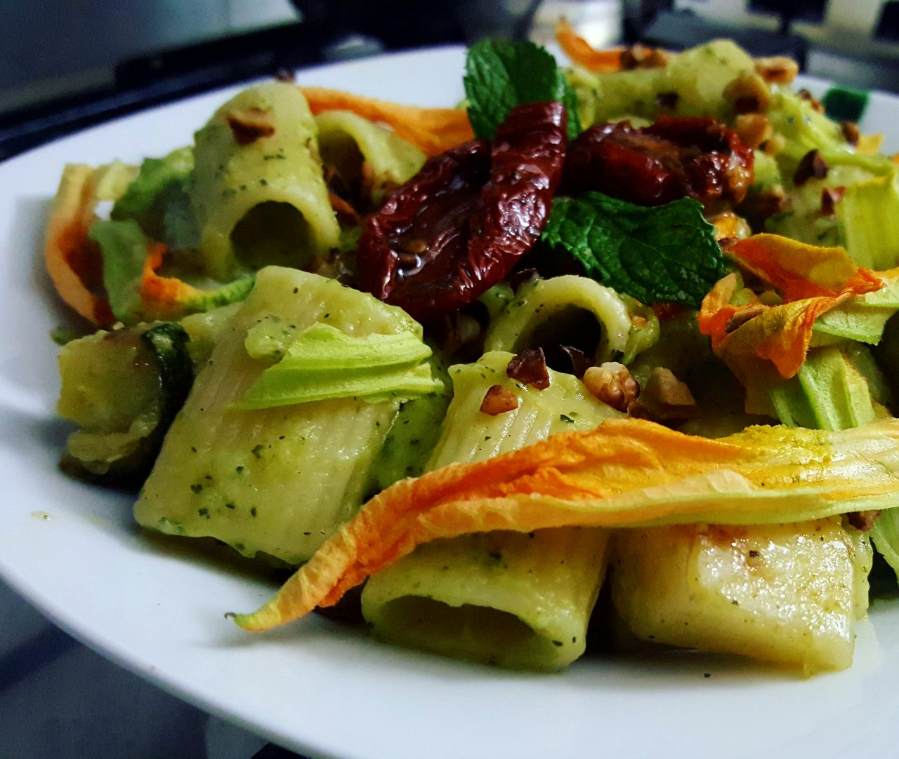 Mezze maniche al pesto di zucchine, con pomodori secchi, nocciole tostate e fiori di zucca