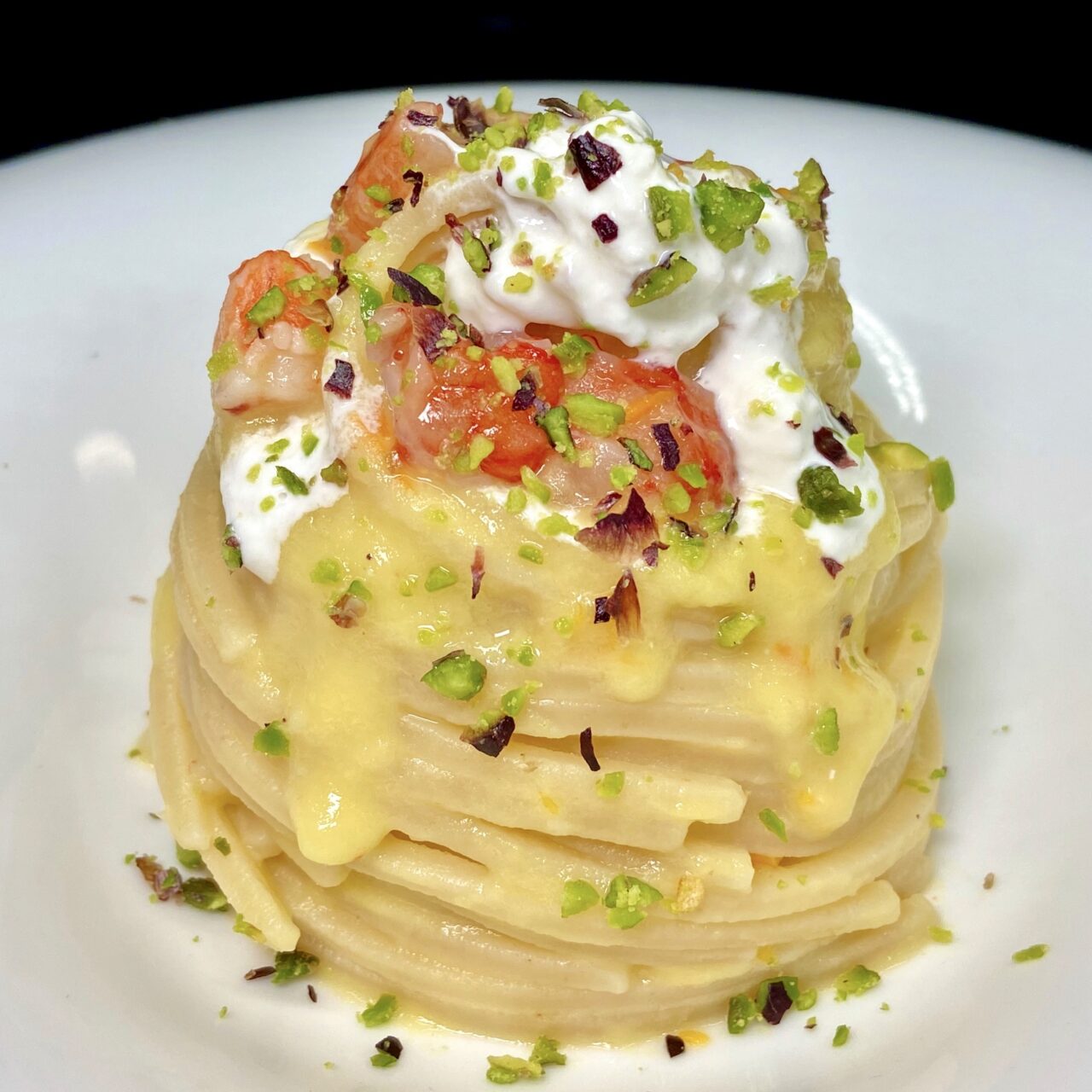 Chitarra con datterini gialli, gamberi, burrata e pistacchi.