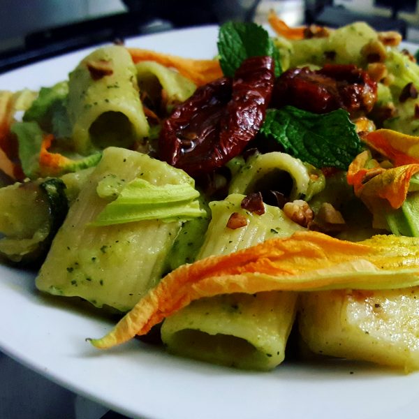 Mezze maniche al pesto di zucchine, con pomodori secchi, nocciole tostate e fiori di zucca