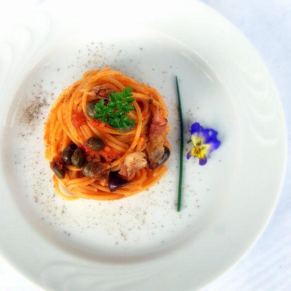 Spaghetti al pomodoro con guanciale croccante, olive taggiasche e capperi